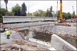 Workers install beams for a bridge on Perrysburg-Holland Road in Toledo. A higher state gas tax could accelerate road construction and repair.