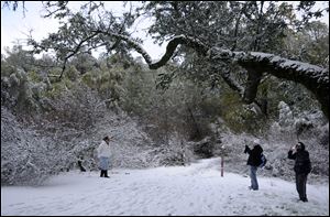 Maria Maldando, left, Gabriel Franko, center, and Arturo Canal, visiting from Jalisco, Mexico, take turns taking each others' picture in the snow at Mount Diablo State Park in Walnut Creek, Calif., Tuesday.
