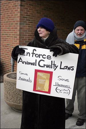 Mary Ellen Coleman of Findlay urges enforce-ment of animal cruelty laws outside Findlay Municipal Court.  