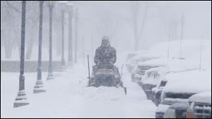 A man clears snow from the sidewalks around Friends University in Wichita, Kan. as heavy snow falls Wednesday morning.