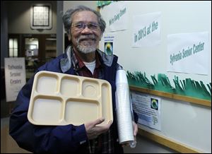 Sylvania Senior Center member Mon Taroy holds an eco-friendly lunch tray and a stack of cups. 