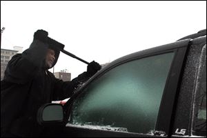 Jock Williams scrapes ice off of his windshield today. Heavy snow and wind slowed traffic and closed schools.