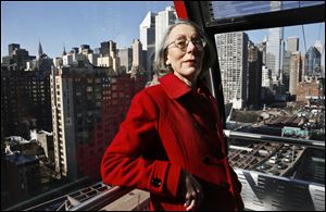 Janet Falk, a public relations professional, rides a tramway with a Manhattan view behind her on Thursday. Ms. Falk applied for a job at a New York City law firm two years ago, but the recruiter told her she wouldn’t be considered because she had been out of work for more than 3 months.