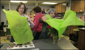 Denise Lumbrezer, left, and Mary Ann Myers, right, wrap floral arrangements while Debbie Myrice, center and rear, squeezes past. Myers, 83, is retired, but she comes in during holiday weeks to help Ken with the arrangements.