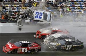 Kyle Larson (32) goes airborne into the catch fence in a multi-car crash including Dale Earnhardt Jr. (88), Parker Kligerman (77), Justin Allgaier (31) and Brian Scott (2) during the final lap today of the NASCAR Nationwide Series auto race at Daytona International Speedway.