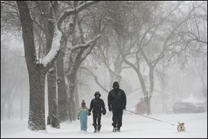 Bob Goodyear walks Rosie, the corgi, as he walks with Suzanne Martin, center, and granddaughter Zoe Martin in front of University Park Elementary Sunday in south Denver.