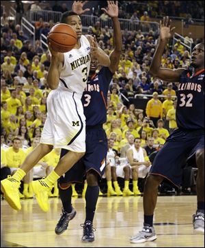 Michigan guard Trey Burke, left, passes as Illinois' Brandon Paul, center, and Nnanna Egwu defend Sunday in Ann Arbor. The Wolverines won 71-58.