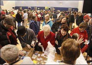 Cousins Becky Degnan of Toledo, center, holding a cup, and JoAnn Riley of Sylvania search for flower seeds at the ninth annual Seed Swap at Woodward High School in Toledo on Saturday.