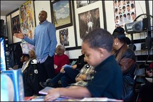 Camarr Burton, 5, right, thumbs through a book as Dennis Hopson, left, address attendees during the 10th Annual Boys Booked On the Barber Shops Program at Blendz Barber Shop in Toledo.
