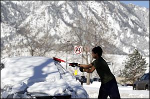 Adnan Reza, a senior engineering student at the University of Colorado, from Dhaka, Bangladesh, removes the snow from his car on a sunny morning following a winter storm, in Boulder, Colo.