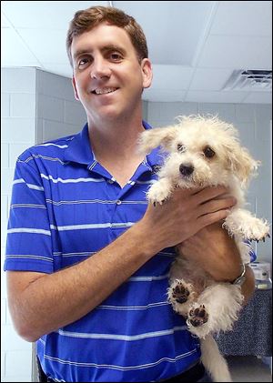 Gary Willoughby, an Ypsilanti, Mich., native, holds an adoptable dog at his former job in South Carolina.