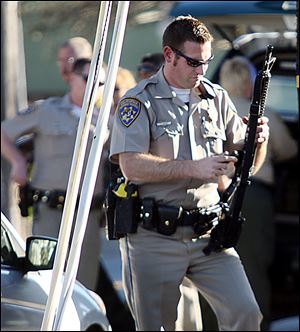 A California Highway Patrol officer loads an ammunition clip into his rifle near the shooting scene in Santa Cruz, Calif., where two Santa Cruz Police detectives were shot and killed Tuesday.