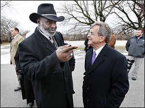 Mayor Mike Bell and Ohio Attorney General Mike DeWine talk about neighborhood issues in front of a home being demolished.