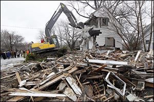 Workers demolish a home on Brewster Street that has sat vacant since 2007, resulting in depressed home values. The Ohio Attorny General’s office is promoting  national mortgage settlement money to help fund the demolitions in blighted neighborhoods. Toledo hopes to remove 900 vacant houses.