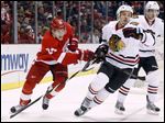  Detroit Red Wings center Damien Brunner (24) tries to tie up Chicago Blackhawks defenseman Niklas Hjalmarsson (4), of Sweden, in the first period today.