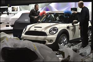 Workers dust a car at the Mini booth during last preparations prior to the opening of the press preview days at the 83nd Geneva International Motor Show in Geneva. The Motor Show will open its gates to the public from Thursday to March 17, presenting more than 260 exhibitors and more than 130 world and European premieres.