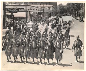 Toledo Pythians shoulder arms in Jubilee Parade. Drill team of Ramadam Temple, Dramatic Order, Knights of Khorassan, swings down Jefferson Ave. with Irving P. Miller, Lambertville, Mich., captain, at far right.  Note the Lorraine Hotel in background on left. Toledo Blade file photo dated May 24, 1948
