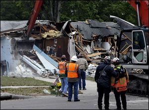 Demolition experts watch as a home is destroyed Sunday after a sinkhole opened up underneath it late Thursday evening swallowing Jeff Bush, 37, 