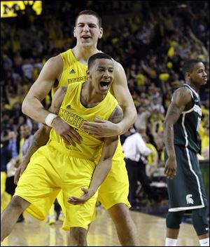 Michigan point guard Trey Burke, front, and forward Mitch McGary celebrate their 58-57 win over Michigan State today Ann Arbor. Trey Burke stole the ball from Keith Appling near midcourt and went in alone for a dunk with 22 seconds remaining, then made another steal in the final seconds to secure the win.