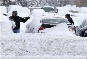 Workers remove snow from cars at an auto dealership today in Bloomington, Minn. left by a storm that is crawling east from the Dakotas and Minnesota toward Chicago which could bring up to 10 inches of snow in some areas.