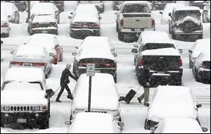 Travelers walk past snow-covered vehicles in the O'Hare International Airport parking lot in Chicago last week.