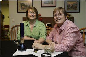 Wearing their wedding rings, Kimberly Bliss, left, and her wife Kim Ridgway, right, with medical marijuana and a water pipe that Ridgway uses to treat arthritis and severe anxiety. 