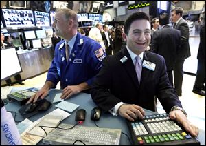 Specialist Christian Sanfillippo, right, smiles as he works at his post on the floor of the New York Stock Exchange.