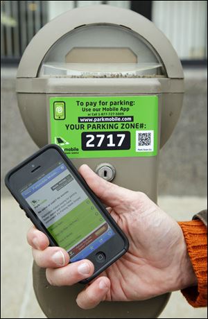 Downtown parking meters have new stickers promoting a pay-by-phone application.