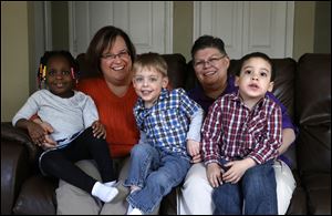 April DeBoer, second from left, sits with her adopted daughter Ryanne, 3, left, and Jayne Rowse, fourth from left, and her adopted sons  Jacob, 3, middle, and Nolan, 4, right, at their home in Hazel Park.
