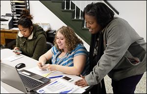 Financial coach Wendy Easler, right, and Nadine Bryant, center, of the United Way help Disarea Segura of Toledo with her taxes at the Financial Opportunity Center in North Toledo.