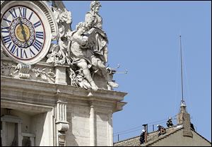 Firefighters, right, place the chimney on the roof of the Vatican's Sistine Chapel, where the cardinals will gather to elect a new pope. The conclave is set to start Tuesday afternoon.