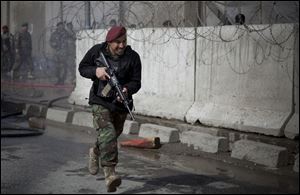An Afghan Army soldier runs outside the Afghan Defense Ministry after a suicide bomber on a bicycle struck outside the ministry, killing at least nine Afghan civilians as U.S. Defense Secretary Chuck Hagel visited Kabul, Afghanistan.
