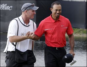 Tiger Woods, right, and his caddie Joe Lacava congratulate each other after winning the Cadillac Championship. Woods shot a 1-under-71 on Sunday to win.