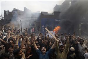 An angry mob reacts after burning Christian houses in Lahore, Pakistan, Saturday.