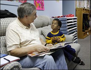 Don Zierolf of Creating Young Readers reads with Demarko Huntley III, 3, at Toledo Day Nursery.