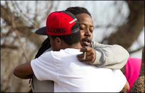 Leaman Joe, left, hugs Michael Parker, at the crash site that killed their friends on Park Ave. in Warren, Ohio, Sunday.