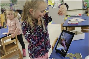 Jessica Baxter, 5, center, shows Kyra Conrad, on the screen at right, the puzzle pieces as she puts them together during class Wednesday afternoon. 