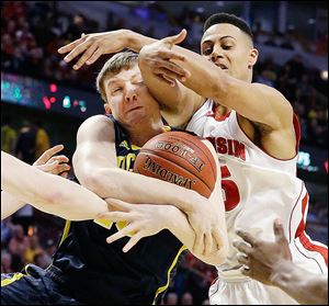 Michigan's Matt Vogrich grabs a rebound in front of Wisconsin's Ryan Evans, right, during the first half of a game at the Big Ten tournament Friday.