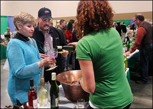 Michigan residents Valarie Cerasuolo and Craig Baker sample Firelands Winery wine poured by Melissa Kadow during the Glass City Wine Festival.
