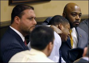 Defense attorney Walter Madison, right, holds his client, 16-year-old Ma'lik Richmond, second from right, while defense attorney Adam Nemann, left, sits with his client Trent Mays, foreground, 17, as Judge Thomas Lipps pronounces them both delinquent on rape and other charges after their trial in juvenile court in Steubenville, Ohio.