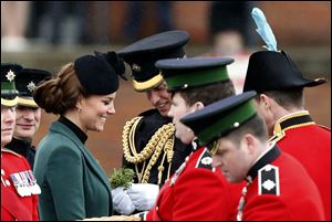 Britain's Kate Duchess of Cambridge, third left, stands with her husband Prince William, fourth left, before presenting traditional sprigs of shamrock to members of the 1st Battalion Irish Guards at the St Patrick’s Day Parade at Mons Barracks in Aldershot, England.