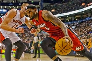 Miami's LeBron James drives past the Raptors' Jonas Valanciunas during the first half of Sunday's game in Toronto. His 22 points and 12 rebounds helped the Heat to their 22nd straight victory.