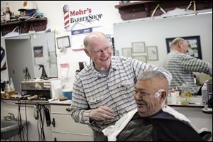 Harold Mohr prepares to shave around the ears of Ray Garcia at Mr. Mohr's barber shop on South Lane Street in Blissfield. The barber has been cutting hair 50 years, following successful completion of training at a barbers' college in Detroit.