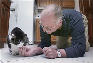 Joe Reynolds on occasion will get down on his hands and knees to feed Kit Kat, who is suffering from kidney disease but is being treated with fluids.