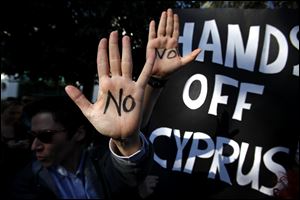 Protesters hold up their hands as they protest outside the parliament in capital Nicosia, Cyprus.