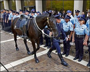 Michael McGee of the Toledo Police Department Mounted Patrol leads the riderless horse, Harley, past fellow officers during the Toledo Area Police Memorial Service honoring officers killed in the line of duty.  Harley was killed in an early morning fire at a horse-therapy farm in Oregon.