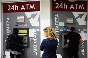A woman waits to use an ATM machine in Nicosia, Cyprus, last week. Cypriots withdrew cash out of fear of a proposed tax on bank deposits.