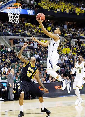 Michigan’s Trey Burke drives on Virginia Commonwealth's Darius Theus in the first half. Burke scored 18 points for the Wolverines.
