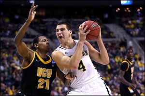Michigan's Mitch McGary drives against Treveon Graham of Virginia Commonwealth. McGary controlled the inside, scoring 21 points to lead the Wolverines (28-7).