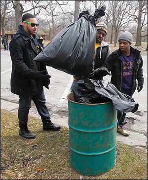 From left, University of Toledo students Jahziel Soriano, Eric Norvell, and Ibrahim Shafau dump collected trash into a can at Ottawa Park.